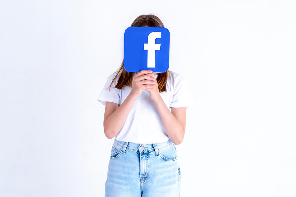 Facebook logo u ruci djevojke na bijeloj pozadini